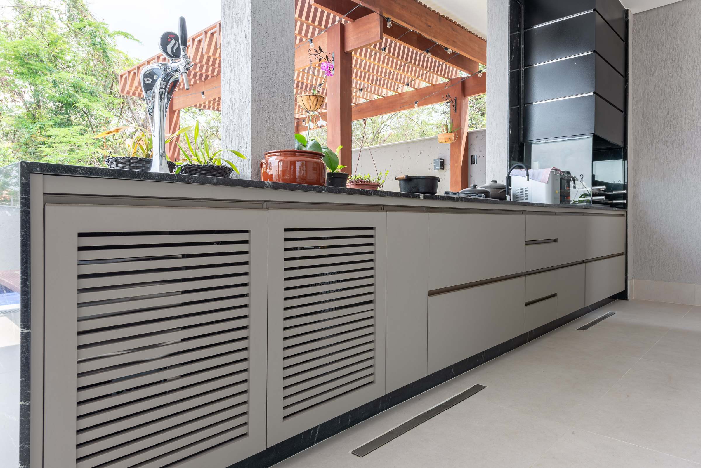 Bancada longa da área gourmet com portas ripadas e gavetas
