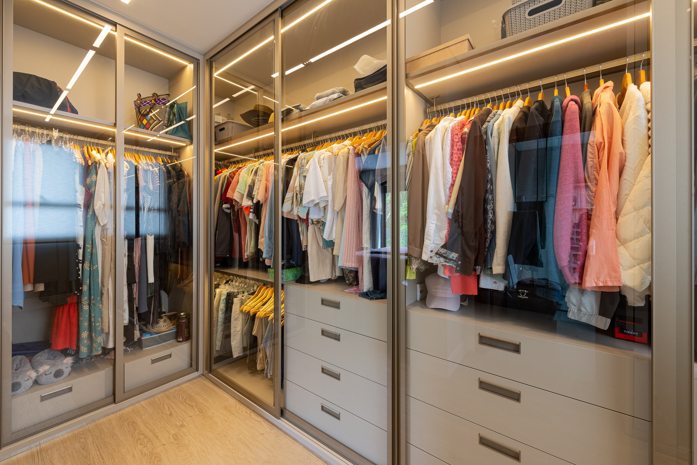 Closet planejado com portas de vidro e iluminação interna